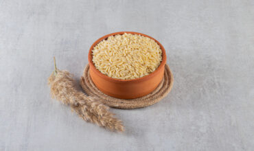 Clay bowl full of raw rice placed on stone background. High quality photo