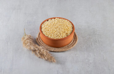 Clay bowl full of raw rice placed on stone background. High quality photo