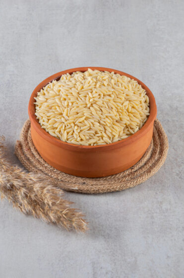 Clay bowl full of raw rice placed on stone background. High quality photo