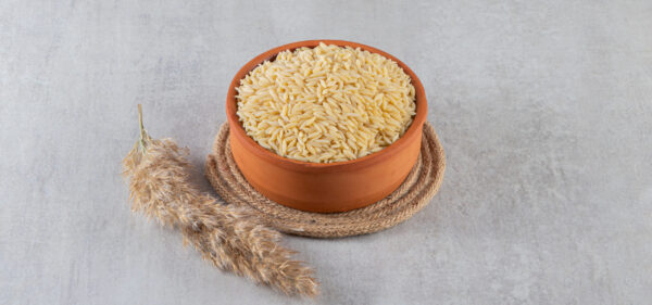 Clay bowl full of raw rice placed on stone background. High quality photo