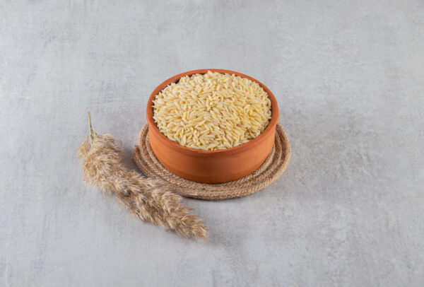 Clay bowl full of raw rice placed on stone background. High quality photo